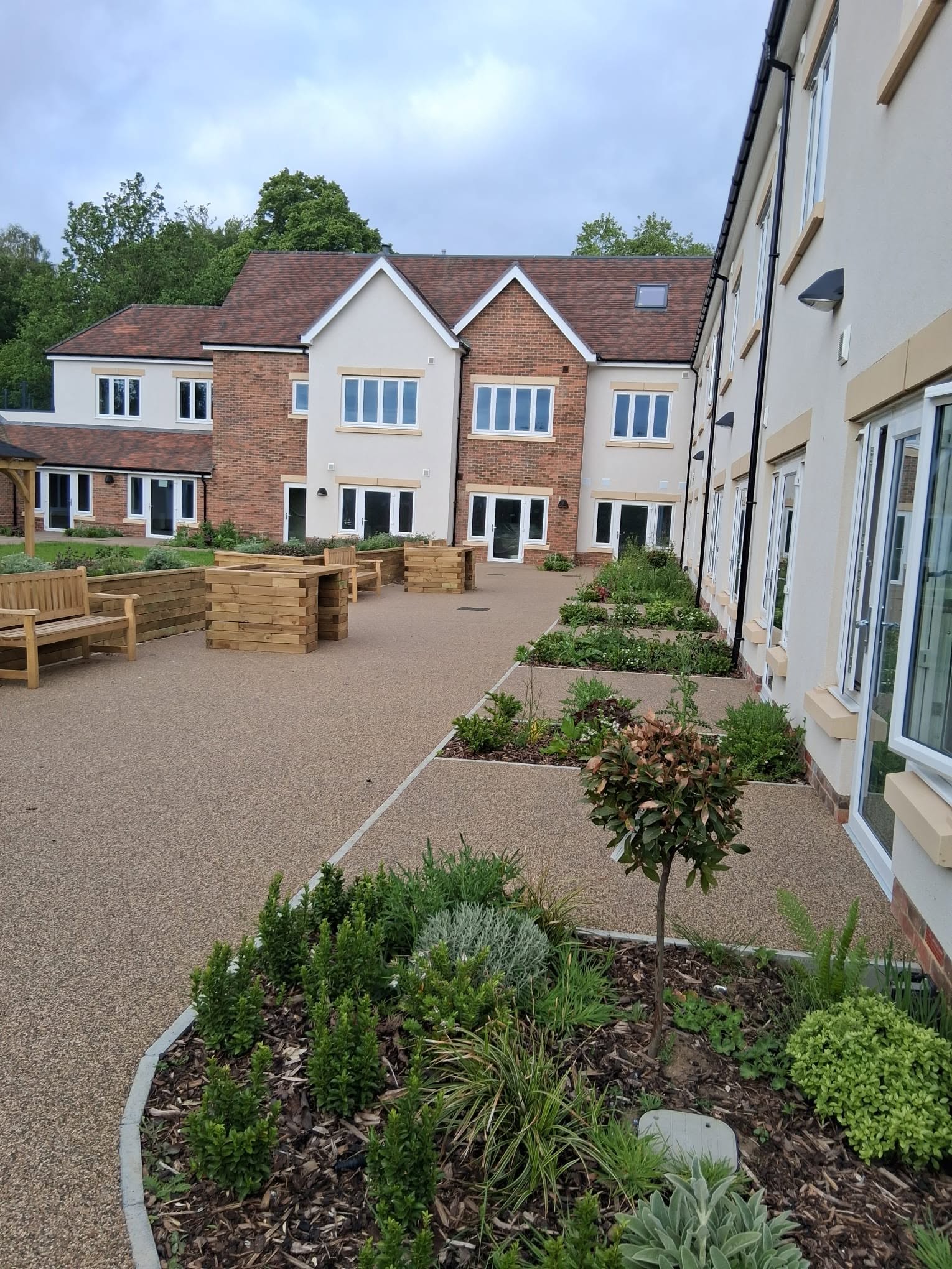 Resin-bound courtyard paths with planting beds and benches outside a new residential building