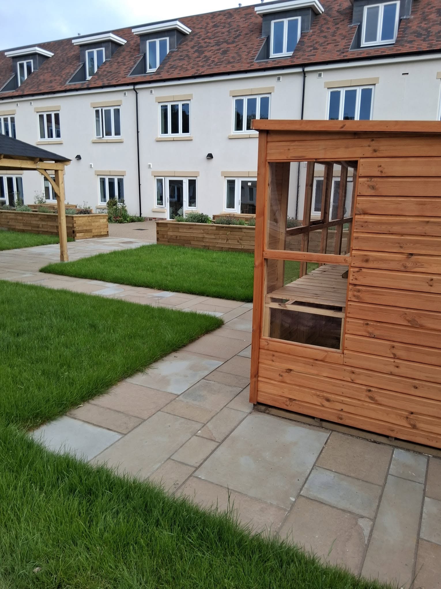 Sandstone paving path across a lawn beside a timber summerhouse