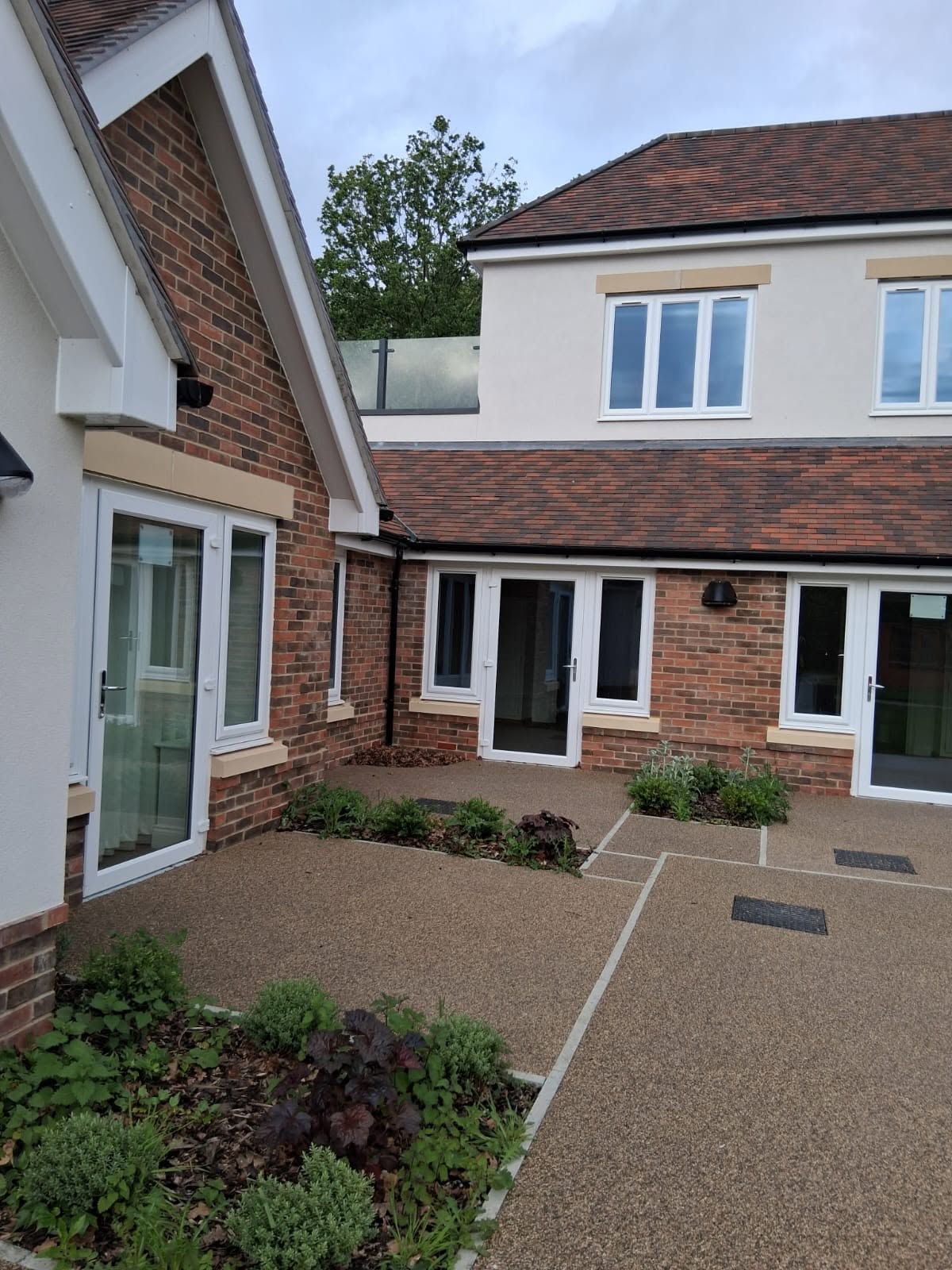 Resin paths and fresh planting beside a brick and render building