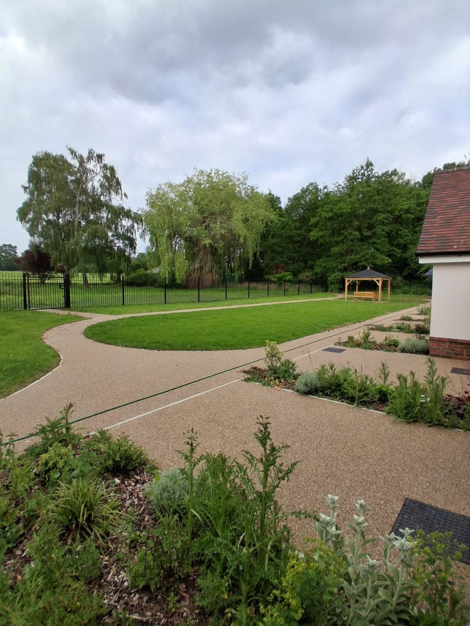 Curving resin path through landscaped grounds towards a gazebo